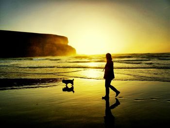 Silhouette of people on beach at sunset