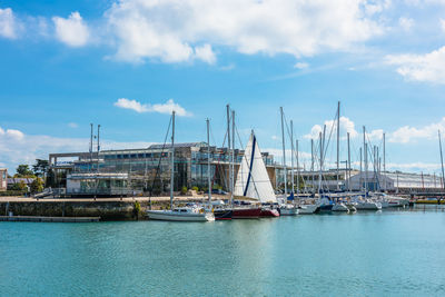 Sailboats moored at harbor against sky