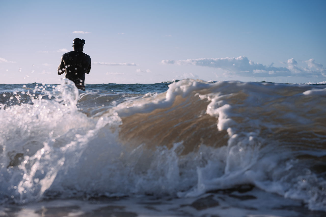 MAN SURFING ON SEA SHORE