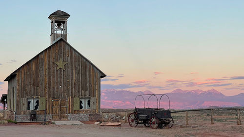Western barn and wagon with the colorful la sal mountain range in the background at sunset