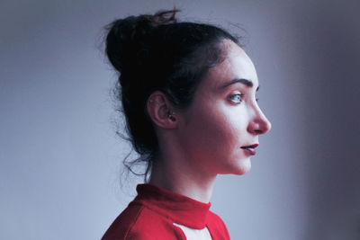 Portrait of young woman looking away against gray background