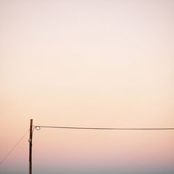 Low angle view of electricity pylon against sky during sunset