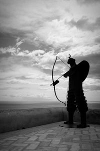 Side view of silhouette statue against clouds