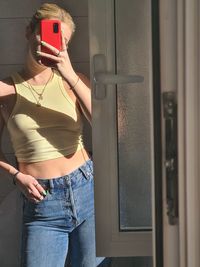 Young woman doing selfie standing in front of mirror