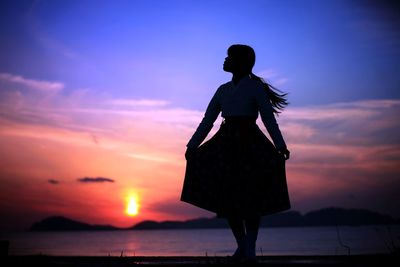 Silhouette woman standing on pier over sea against sky during sunset