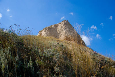 Low angle view of rocks on field against blue sky