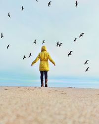 Woman in a yellow coat on a beach