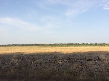 Stone wall on field against sky