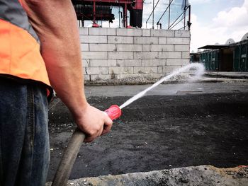 Midsection of man holding umbrella against water