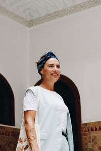 Portrait of young woman standing against wall