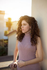 Beautiful young woman standing against wall