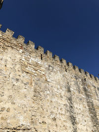 Low angle view of wall against clear blue sky