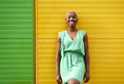 Happy young woman standing in front of green and yellow wall