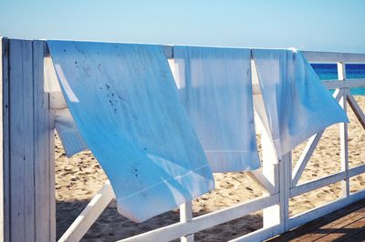 Towels on railing at beach against sky