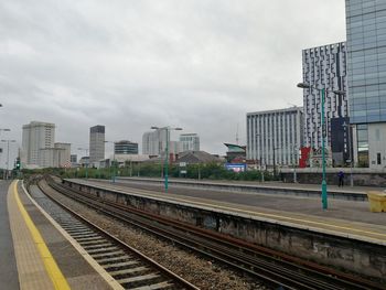 Railroad tracks in city against sky