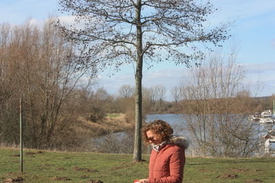 Portrait of woman standing by bare trees on field