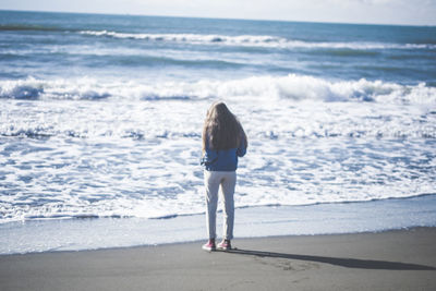 Rear view of woman standing on beach