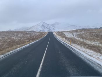 Road leading towards mountain range against sky