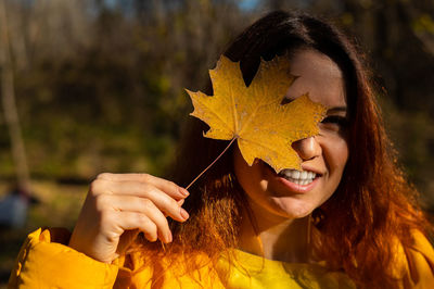 Close-up of woman holding autumn leaf