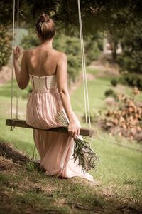 Rear view of woman sitting on grassy field