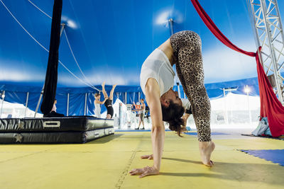 Female artist bending forward while standing on tiptoe at circus