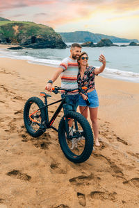 Couple with fat bike taking a selfie with the mobile on the beach