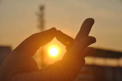 Silhouette person holding sun during sunset