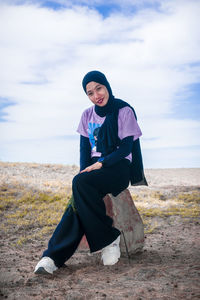 Full length of woman sitting on field against sky