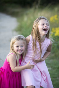 Young sisters laughing in pink summer dresses