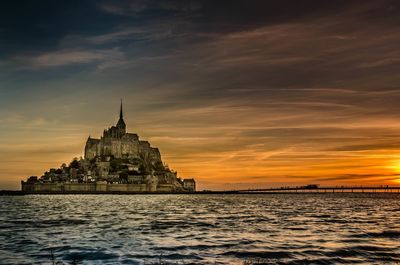 Le mont-saint-michel by sea against sky during sunset