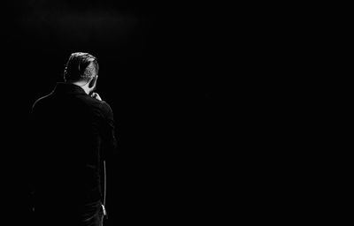 Rear view of woman standing against black background