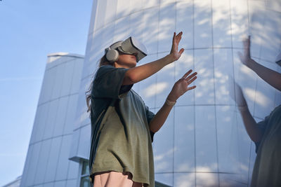 Low angle view of man with arms raised standing against sky