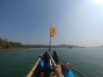 People sitting on boat against clear sky