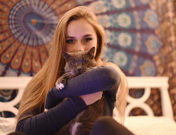 Portrait of beautiful young woman sitting with cat at home
