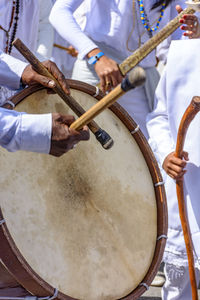 Midsection of man playing drum by crowd during festival 