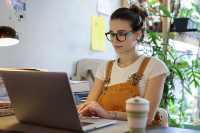 Female flower shop owner taking online customer orders, young woman gardener working on laptop