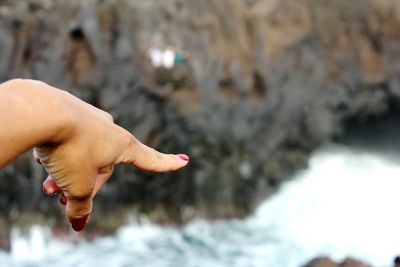 Cropped hand of woman pointing at river