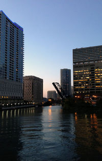 Modern buildings by river against sky in city