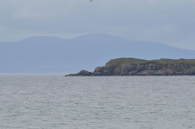 View of calm sea against mountain range