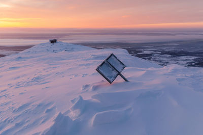 Scenic view of snow covered land against sky during sunset