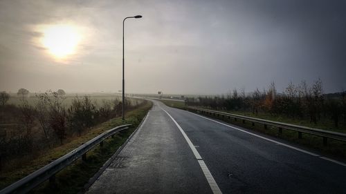 Road amidst trees against sky