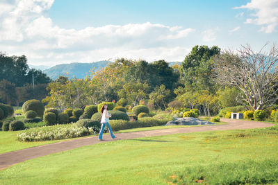 Rear view of woman walking on field against sky