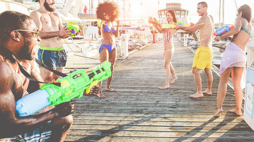 Friends playing with squirt gun in sunny day