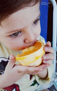 Close-up of cute boy eating orange fruit at home