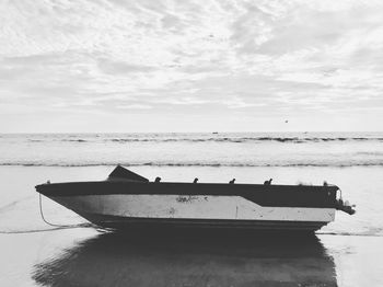 Boat moored on beach against sky