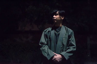 Young man standing on field at night
