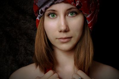 Close-up portrait of young woman against black background