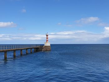 Lighthouse by sea against sky