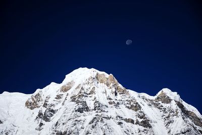 Low angle view of snowcapped mountain against blue sky