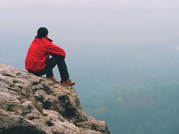 Rear view of man standing on rock against mountain